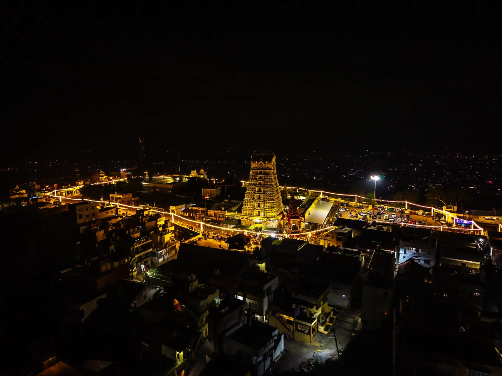Sri Chamundeshwari Devi Temple illuminated at night on Chamundi Hill, aerial view